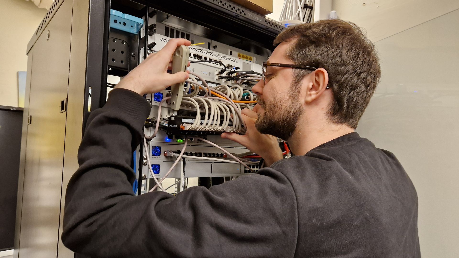 Tekniker som justerer ledningene inne i et serverrack i et datasenter