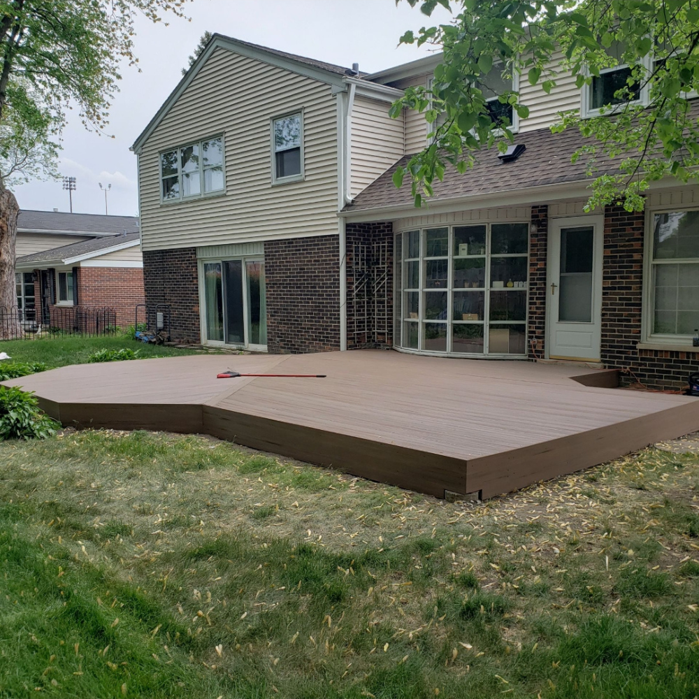 Backyard deck beside a two-story house with sliding glass doors and a grassy lawn