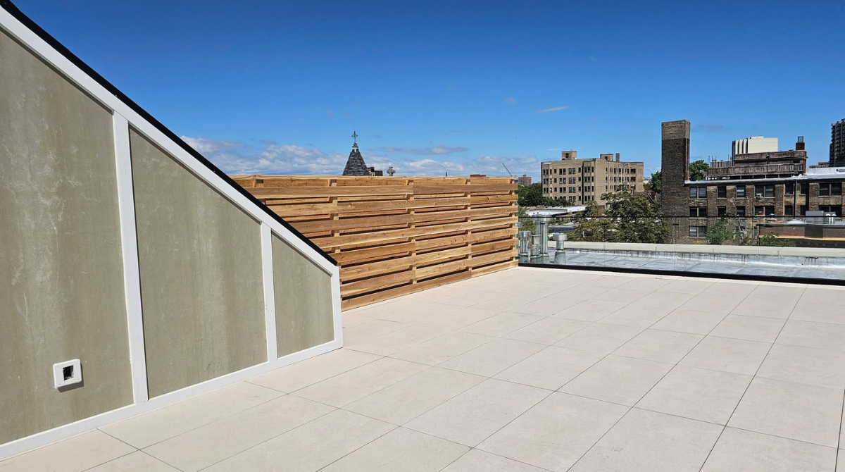 Modern rooftop terrace with white tile flooring, wood slat wall, and city skyline view