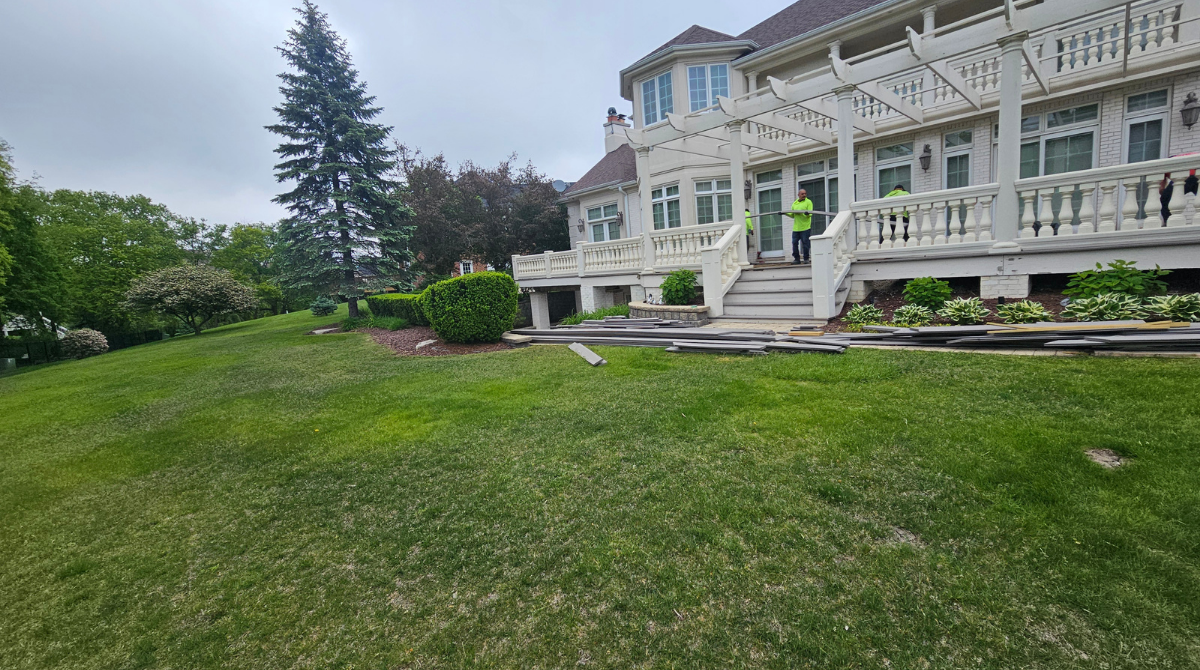 Large white Victorian house with ornate trim beside a green lawn and trees