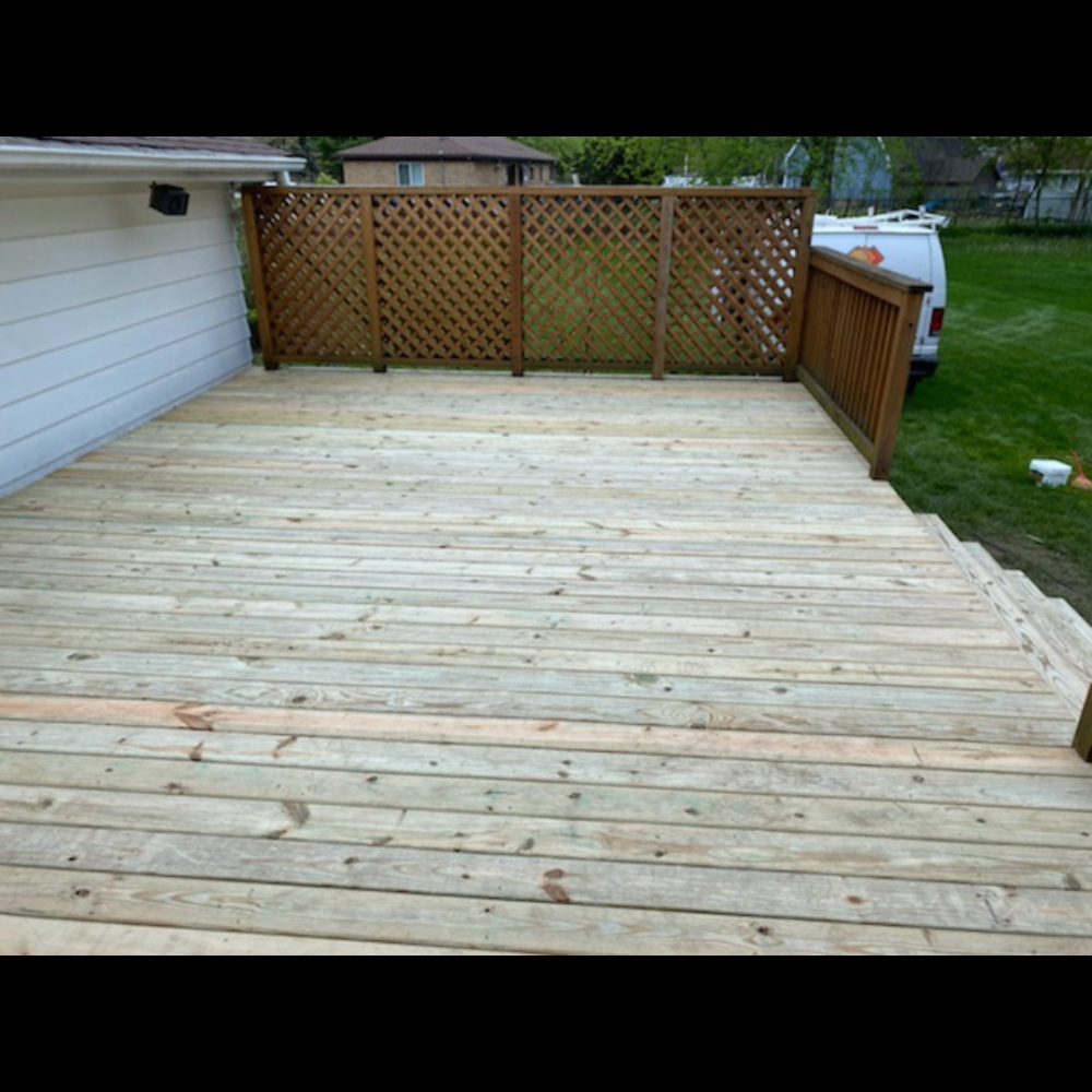 Wooden backyard deck with lattice privacy fence and a small side railing, viewed from the house.