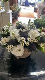 Bouquet di rose color crema e bianche con foglie di eucalipto, legato con un nastro beige su uno sfondo semplice