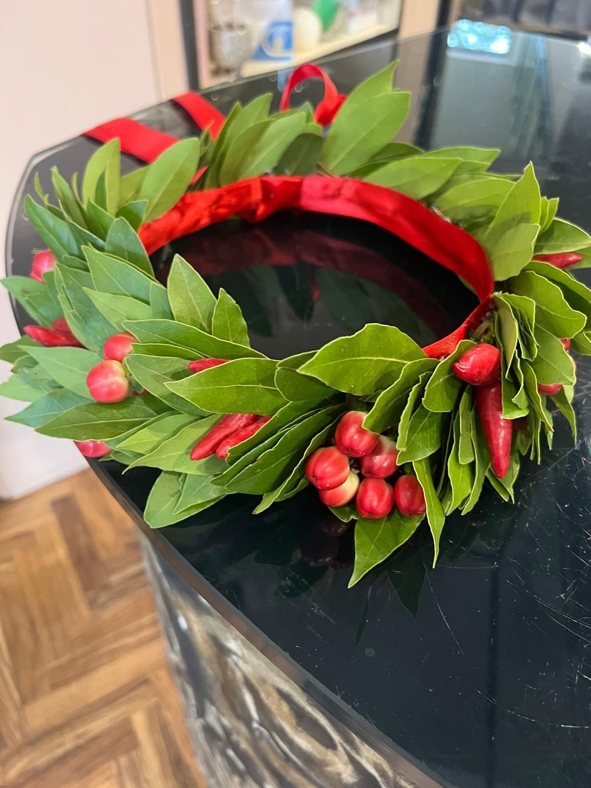 Ghirlanda di foglie rosse con boccioli rosa su una borsa nera, al chiuso.