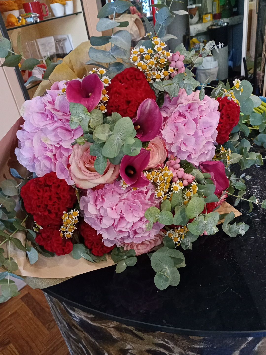 Un assortimento di fiori rosa, rossi e verdi disposti in un bouquet su un tavolo
