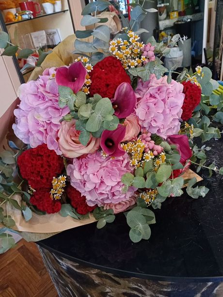 Bouquet di rose e tulipani colorati avvolto in carta marrone e legato con un nastro, su un tavolo vicino alla finestra