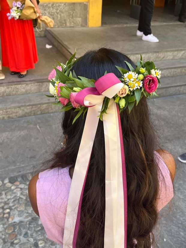 Ghirlanda floreale variopinta con foglie verdi e fiori viola, rosa e bianchi su una superficie nera