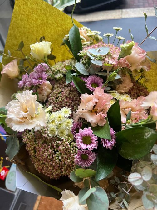 Bouquet di fiori viola con cardi ed eucalipto su un pavimento di legno