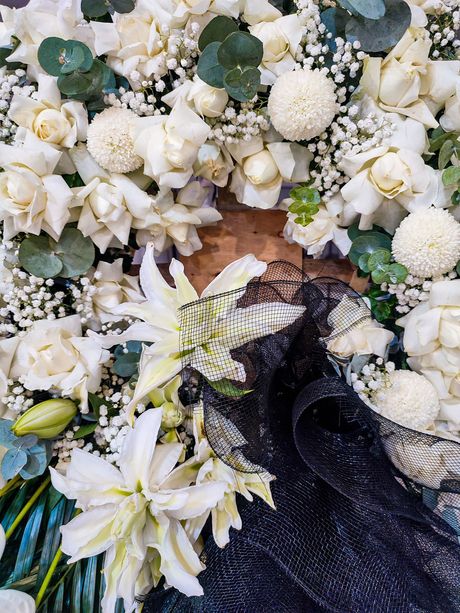 Persona con un abito nero di paillettes distesa tra fiori bianchi e vegetazione