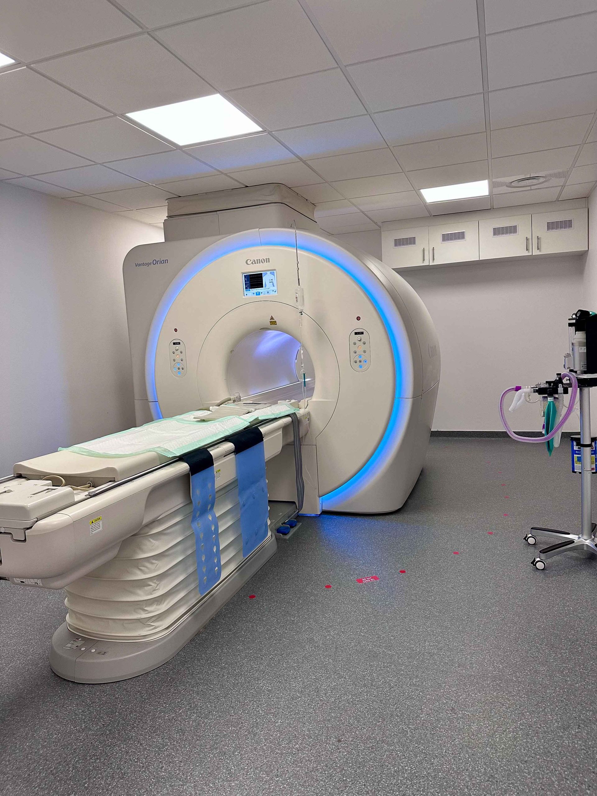 Scanner CT dans une pièce lumineuse ; table d’examen dépliée ; détail de l’éclairage bleu.