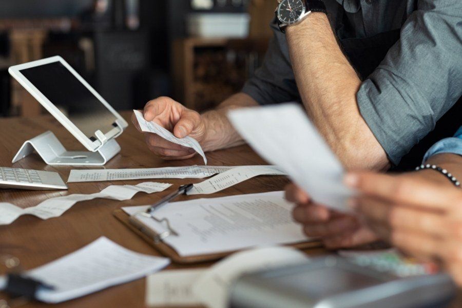 Two people reviewing receipts and documents at a table with a tablet.