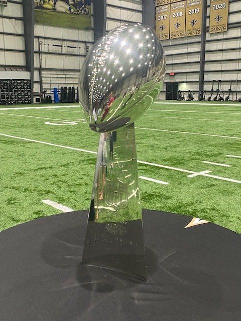 Super Bowl trophy on a table in a football field.