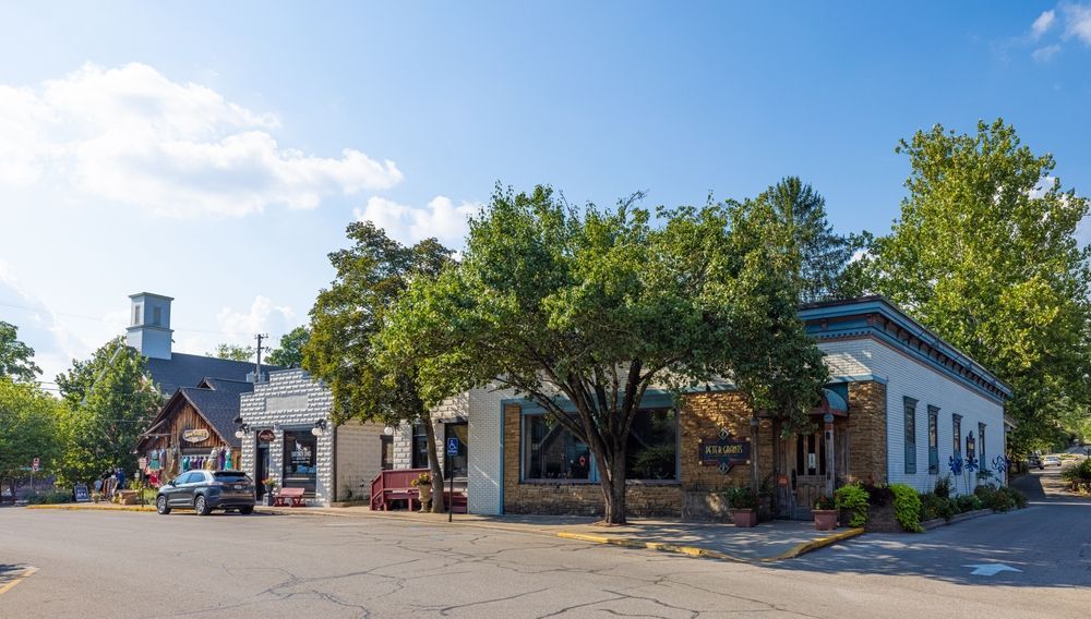 Buildings on a street corner with trees in front. Sunny day.