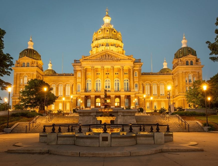 Iowa State Capitol building at dusk, illuminated with golden light.