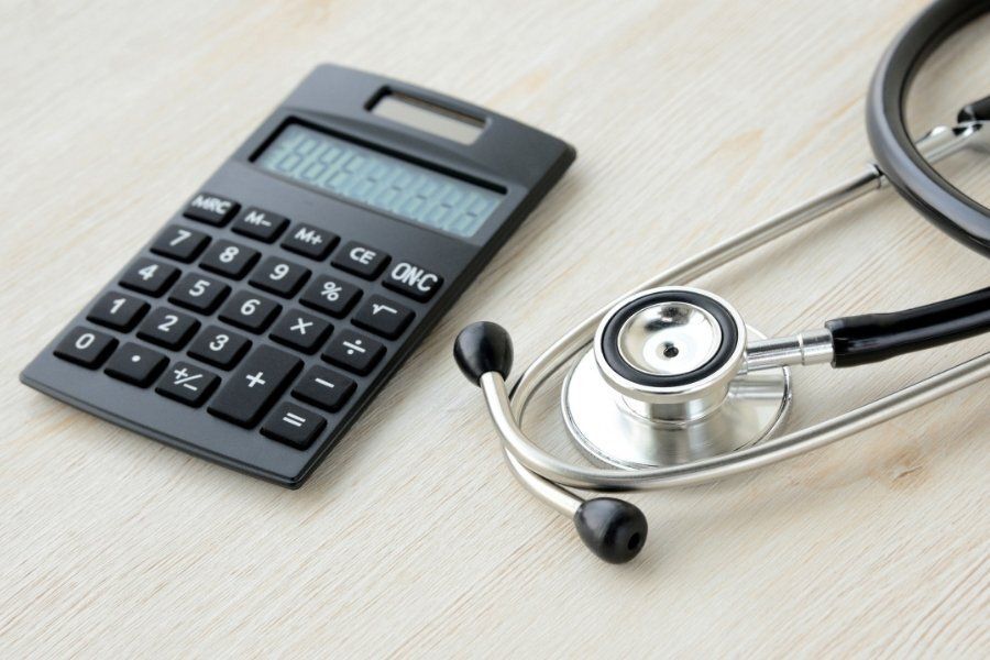 Calculator and stethoscope on a light desk, suggesting medical billing or healthcare finance