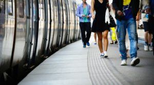 People walking on a train platform next to a train; blurred motion.