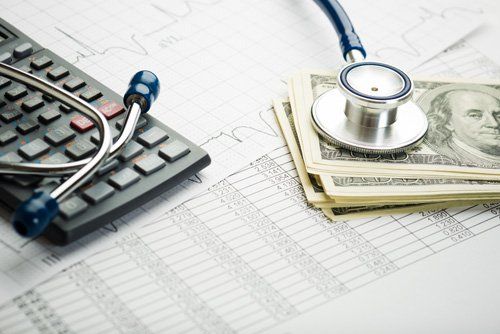 Calculator, stethoscope, money, and papers, symbolizing healthcare costs.