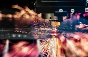 Laser cutting metal, with bright sparks and focus on the cutting head.