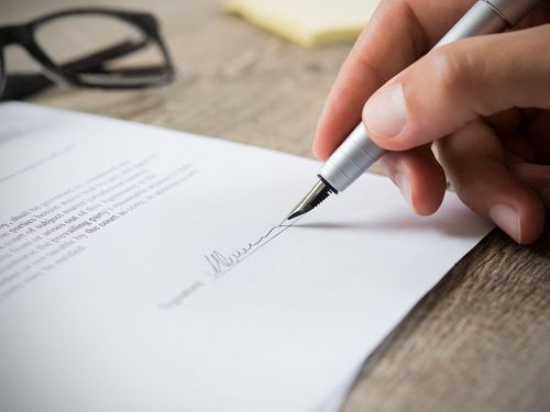 Modern living room with green sofa, fireplace, large wall TV, and wooden chairs near bright windows.