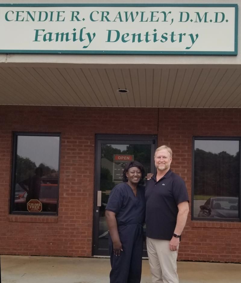 Two people standing outside Cendie R. Crawley, D.M.D. Family Dentistry building