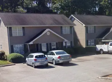 Apartment building parking lot with two cars in front and a white van on the right