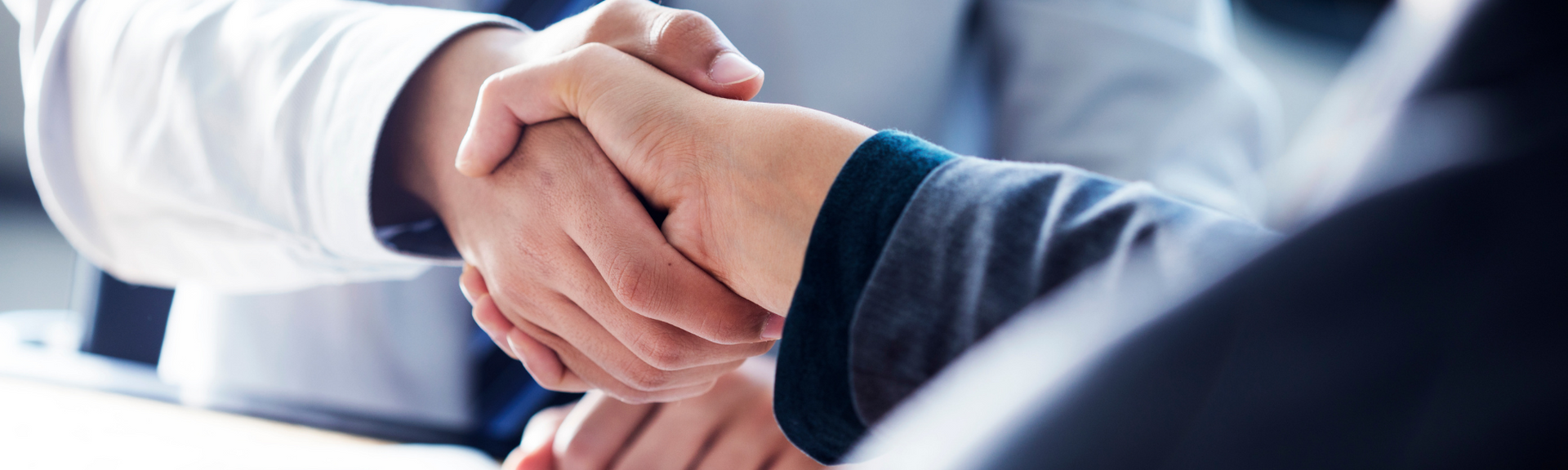 Two people in business attire shaking hands in a bright office