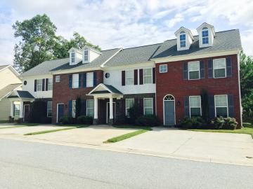Two-story brick apartment building with white trim, red shutters, and attached garages on a quiet street