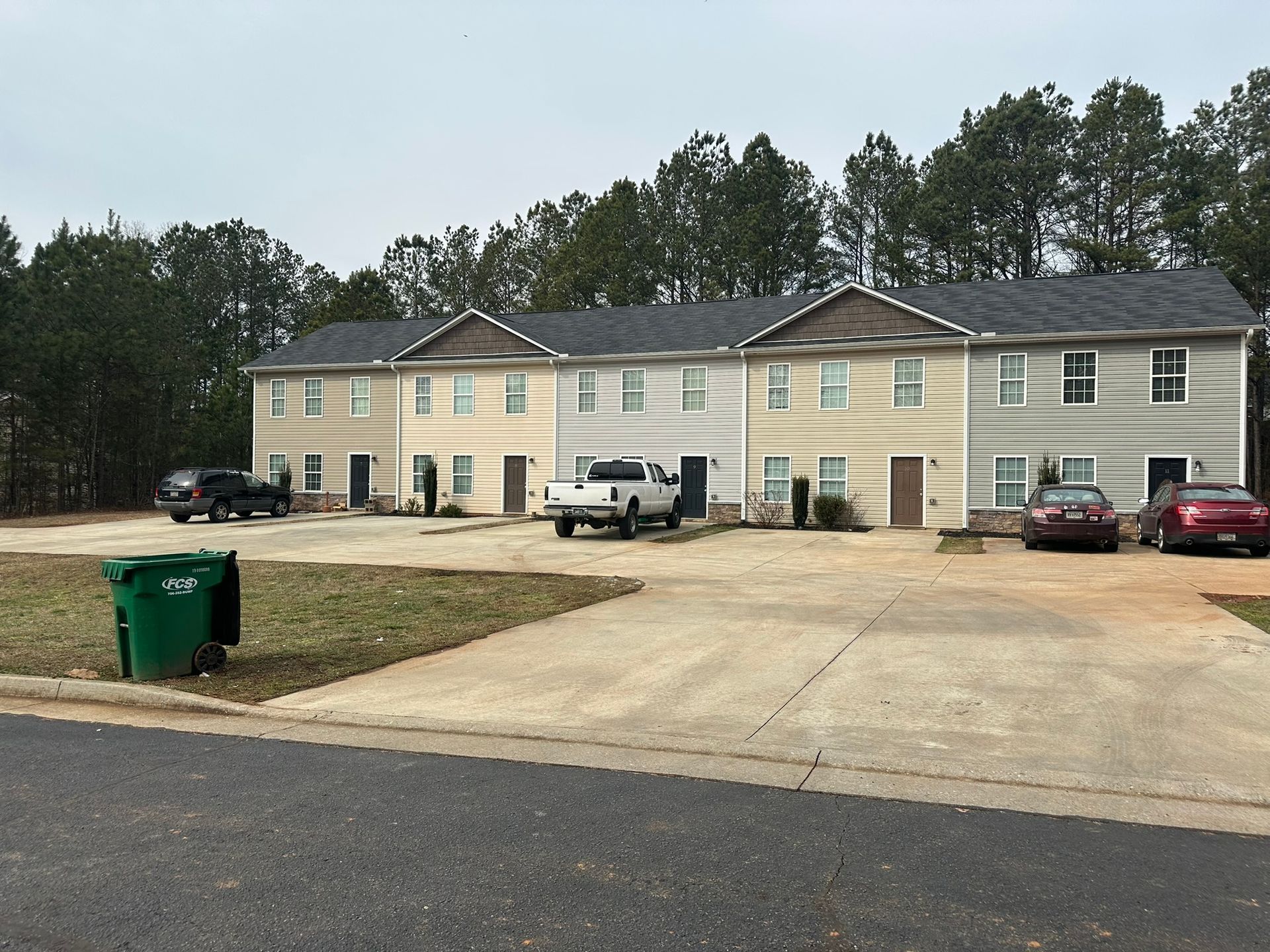 Two-story beige apartment building with parked cars and a driveway
