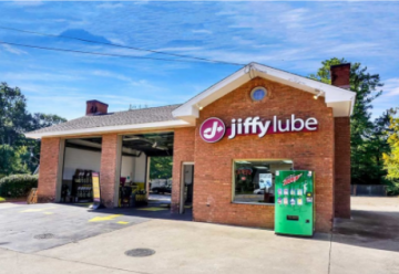 Jiffy Lube auto service center with brick facade and green vending machine under a blue sky