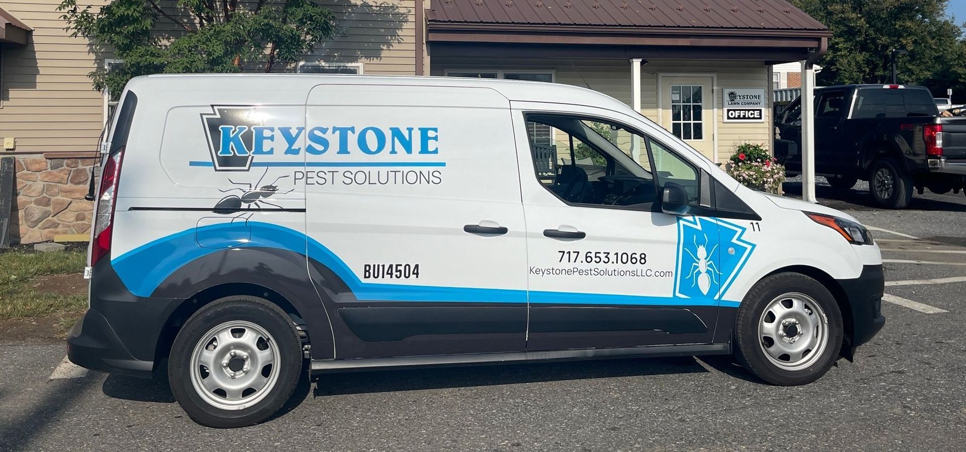 A keystone pest solutions van is parked in front of a building.