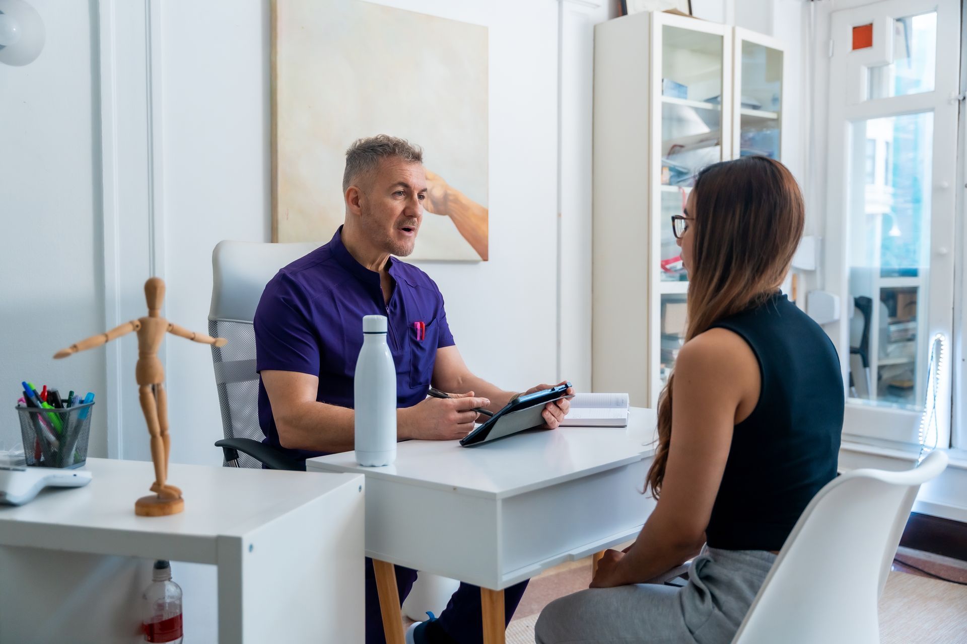 Doctor talking with a seated patient in a bright clinic office