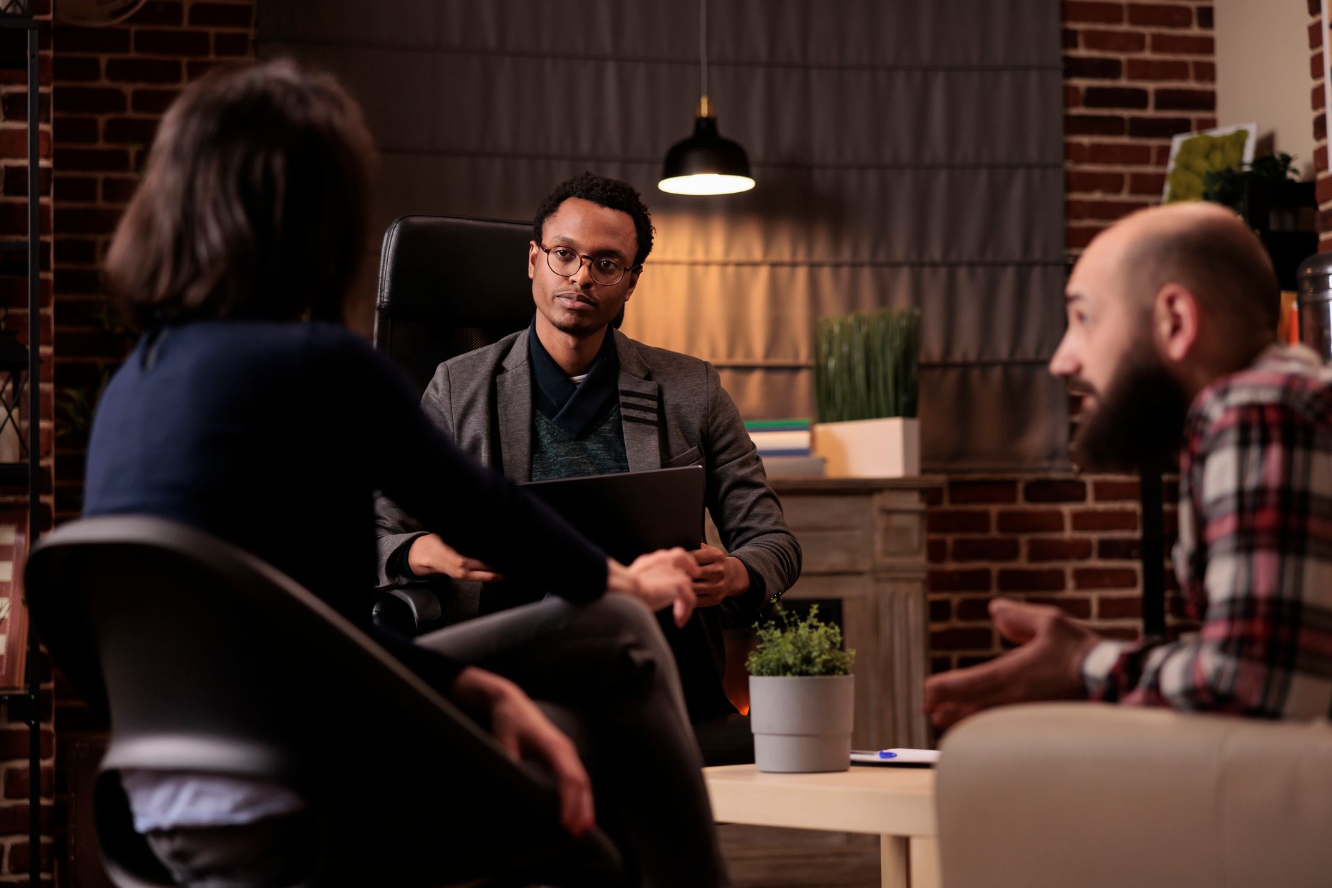 Three people in conversation around a table in a cozy, dimly lit room