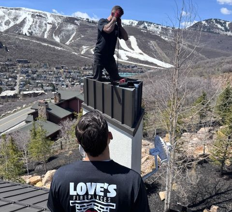 Person standing atop a metal structure overlooking a mountain town and snowy ski slopes