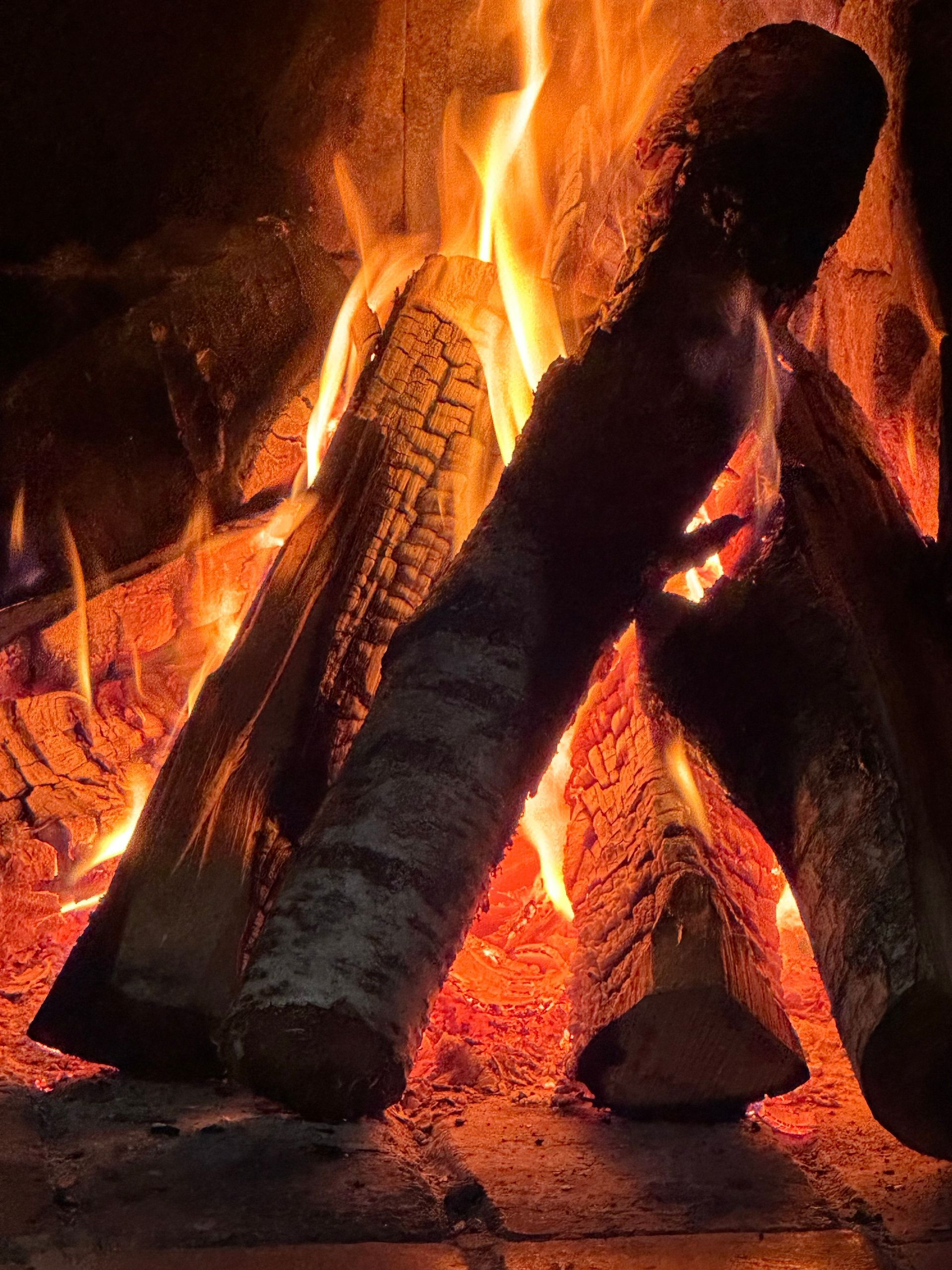 Glowing fire in a fireplace with orange flames and burning logs