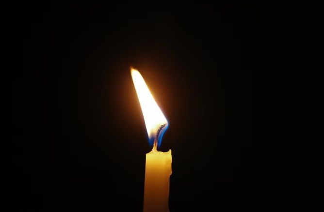 Lit candle flame against dark background, funeral homes Bedford Park, IL remembrance setting.