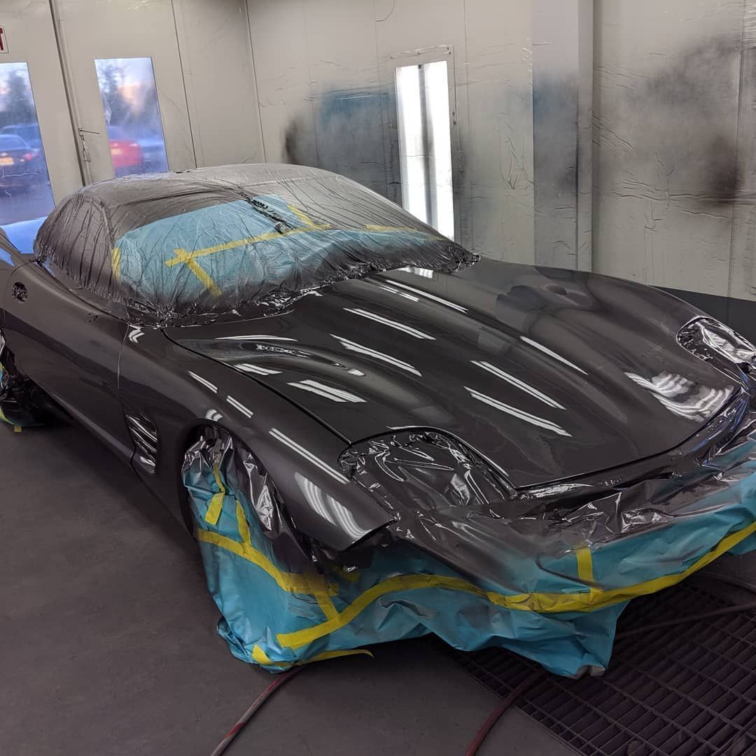 Hands polishing a white car hood with a blue buffer in a garage