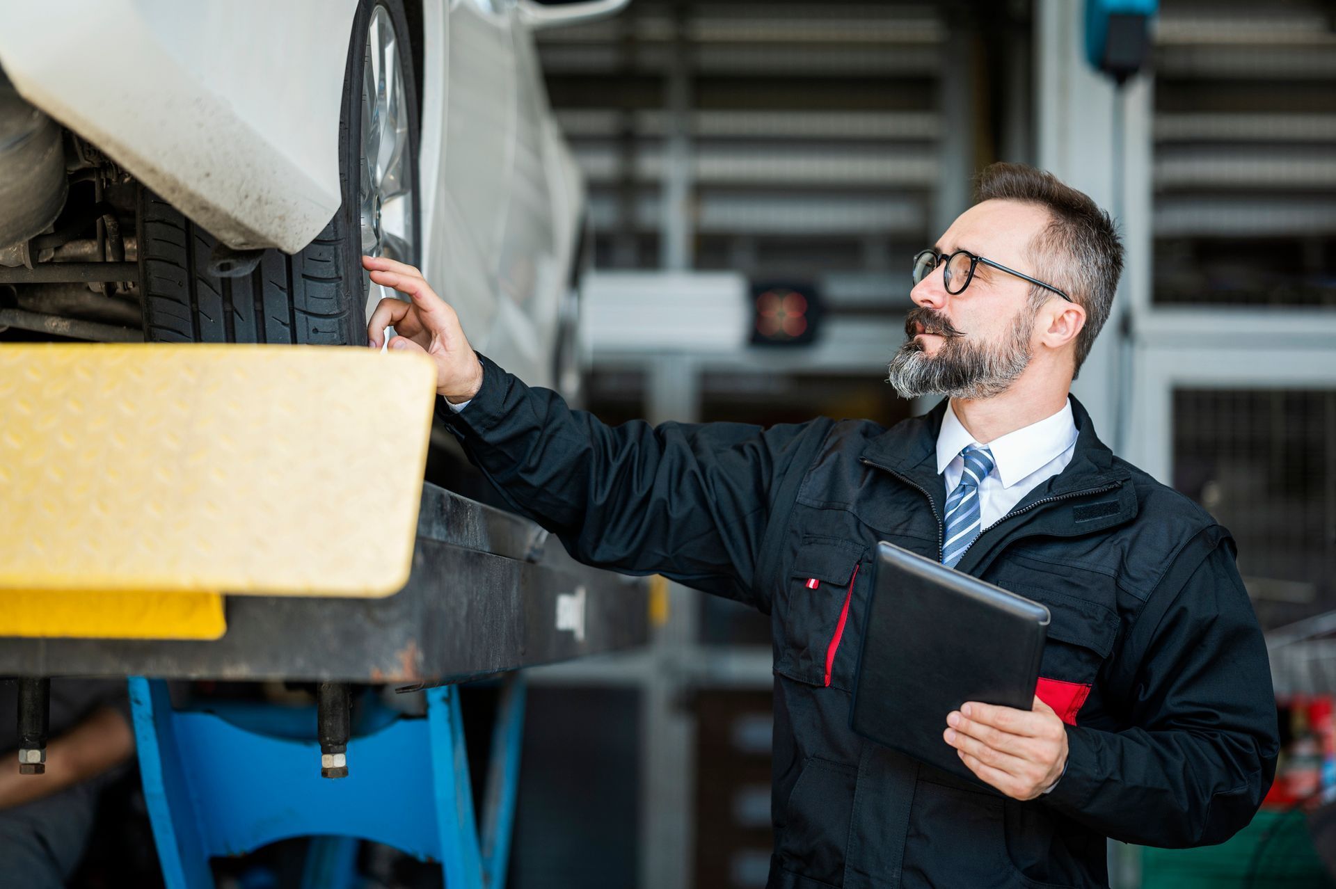Technician inspecting a large machine in a workshop while holding a tablet
