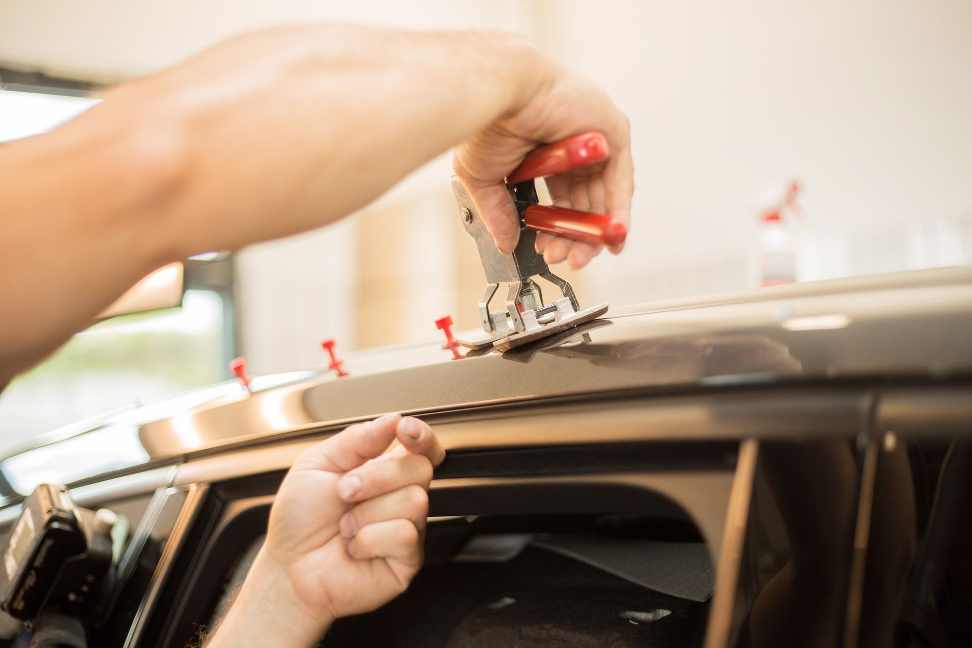 Hands using a suction cup tool to install a roof panel on a car