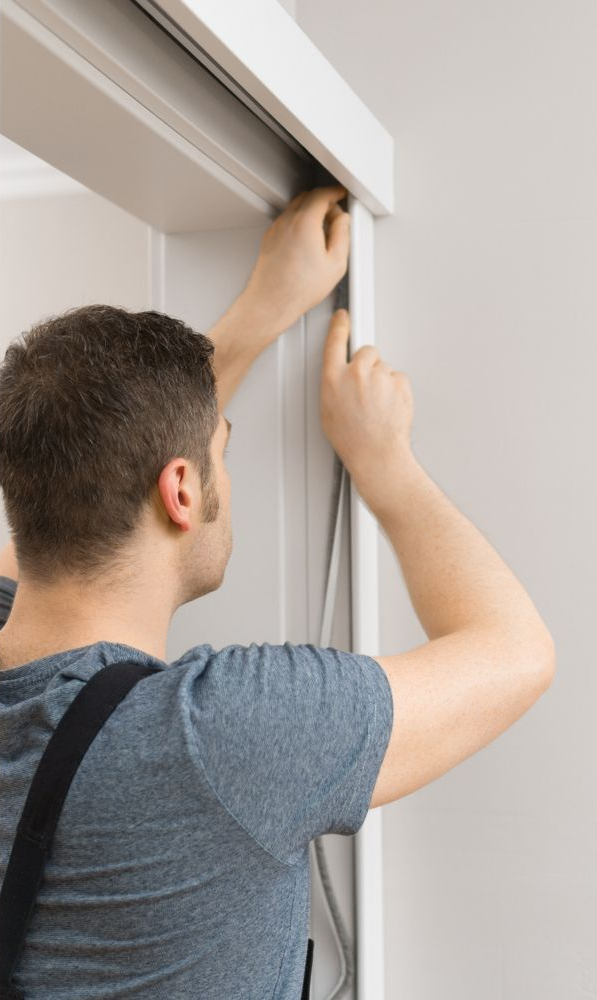 Man installing weatherstripping on a white doorway frame — A Plus Project Maintenance in Wodonga, VIC