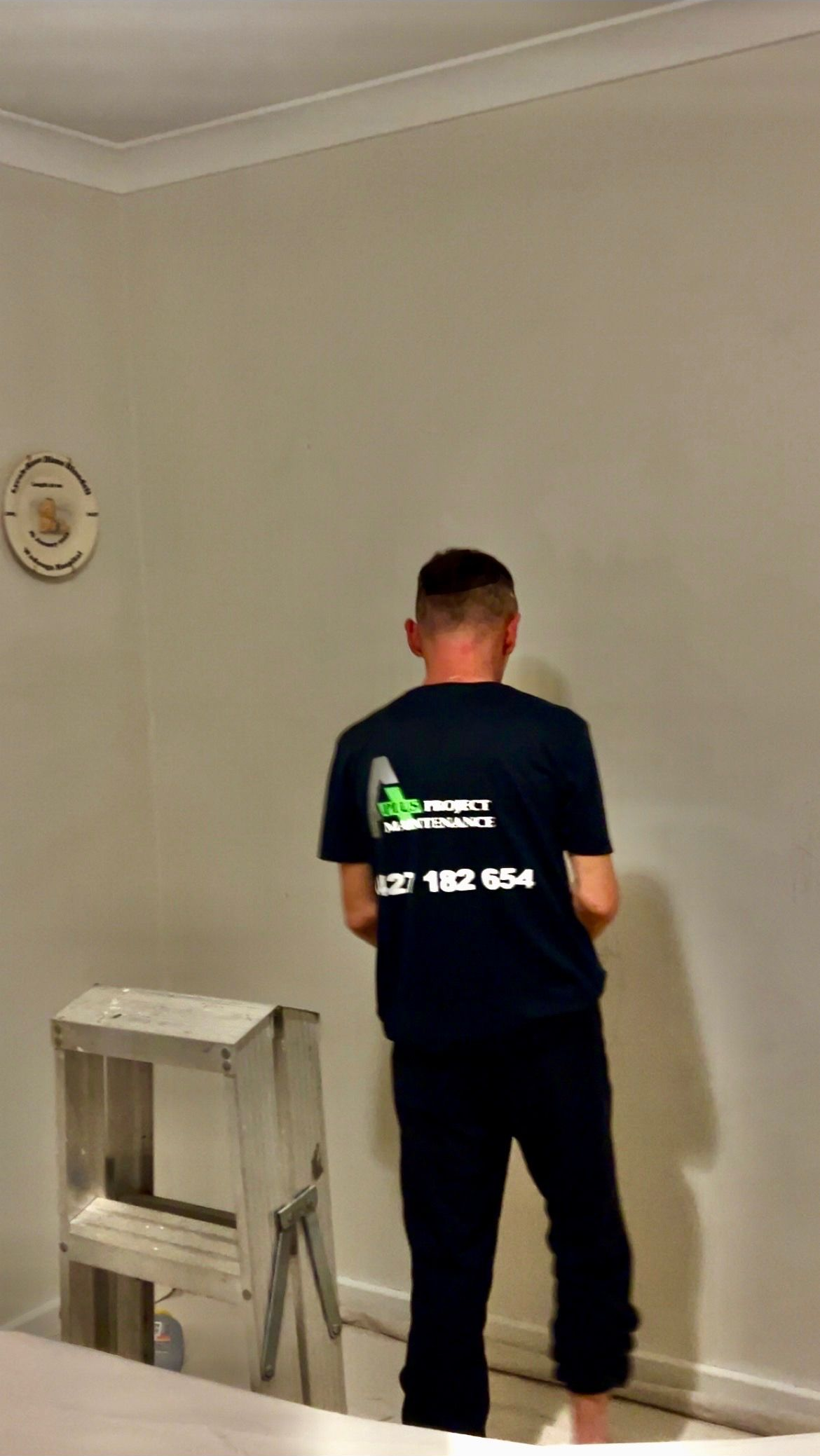 Person in a dark uniform painting a light gray wall in an empty room — A Plus Project Maintenance in Wodonga, VIC