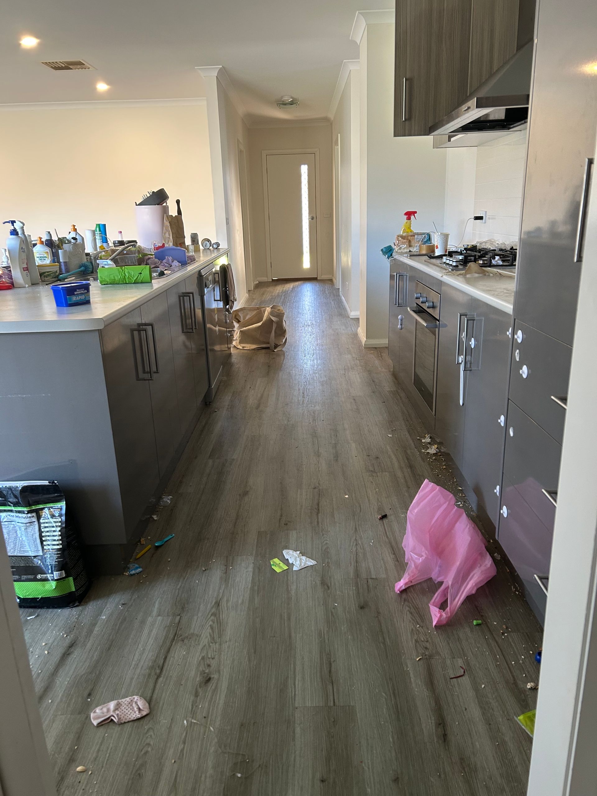 Messy Kitchen With Scattered Trash, Dark Cabinets, and a Pink Bag on the Floor by the Counter — A Plus Project Maintenance in Wodonga, VIC