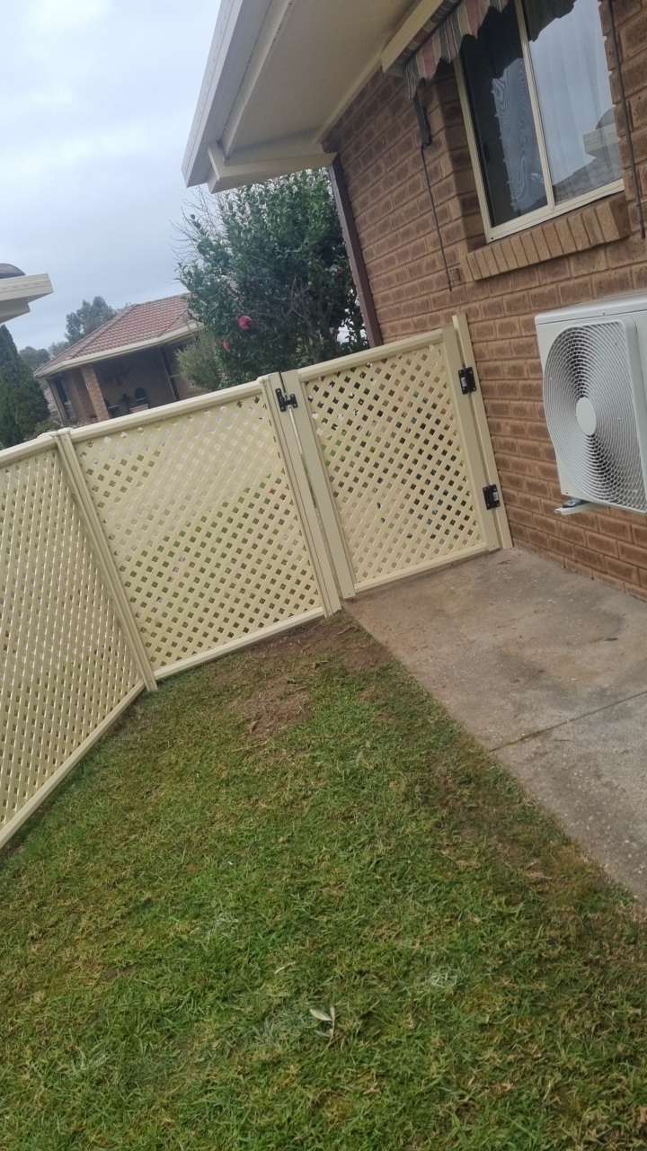 Brick House With White Lattice Fence, Grassy Yard, and a Concrete Path Beside a Window AC Unit — A Plus Project Maintenance in Wodonga, VIC