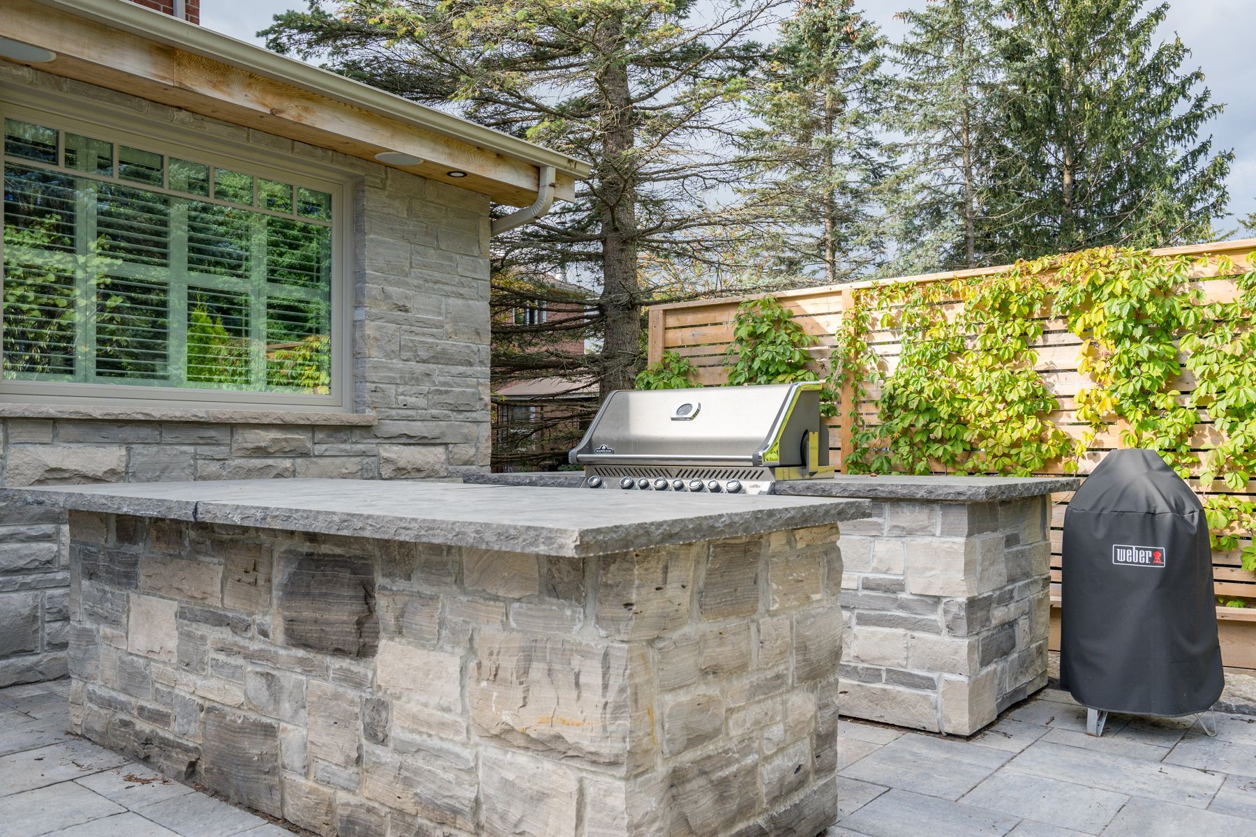An outdoor kitchen with a grill and a brick counter top.