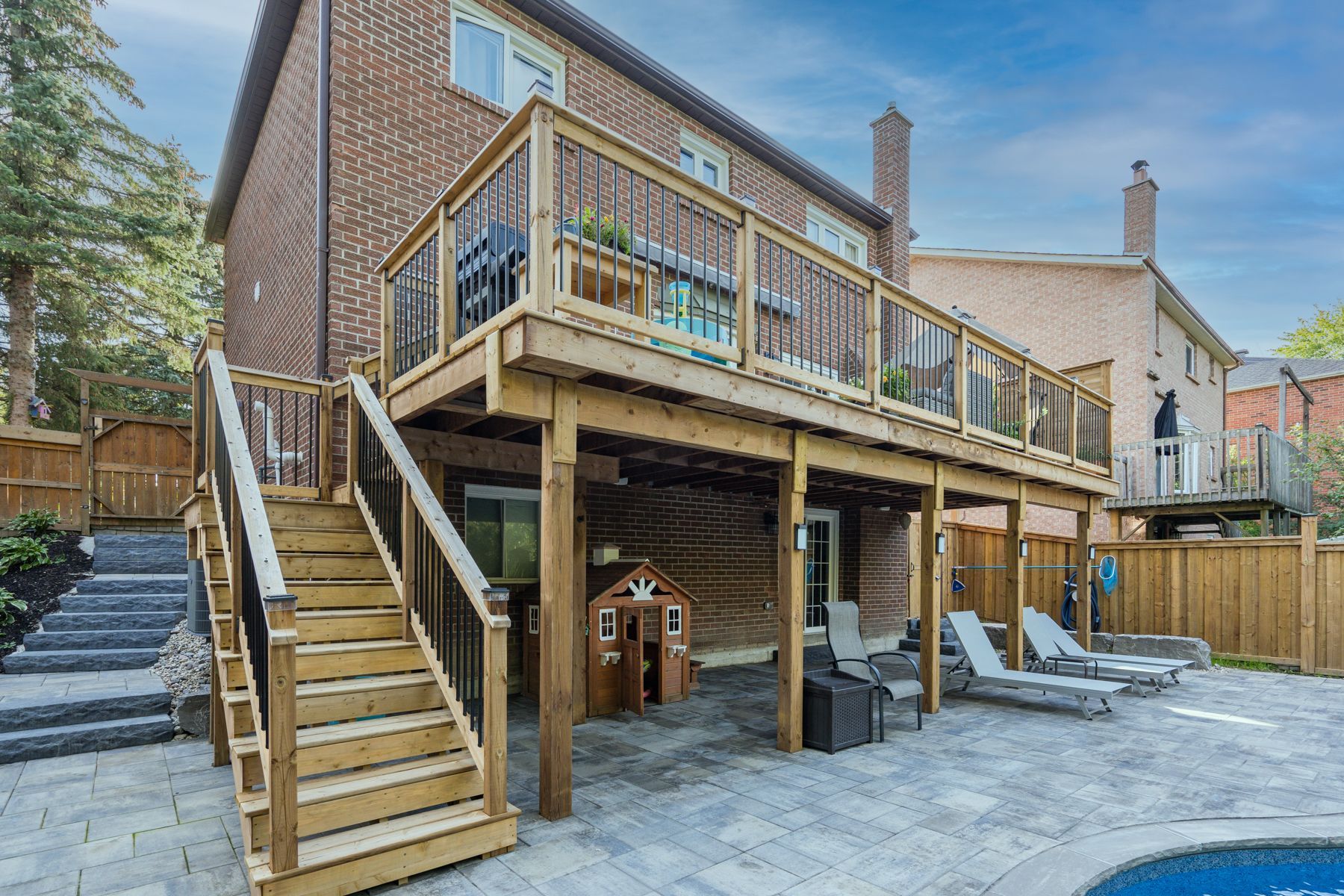A large wooden deck with stairs leading up to it next to a swimming pool.