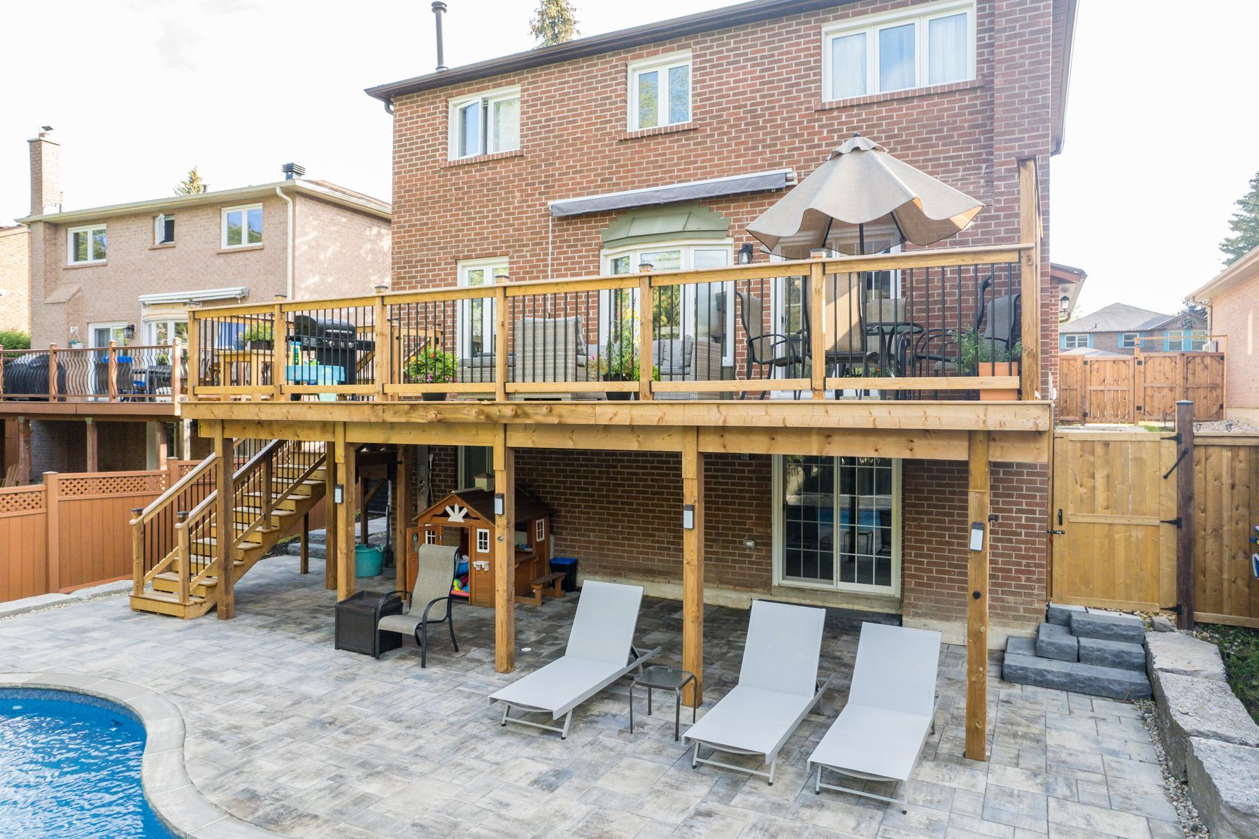 The backyard of a house with a large deck and a pool.