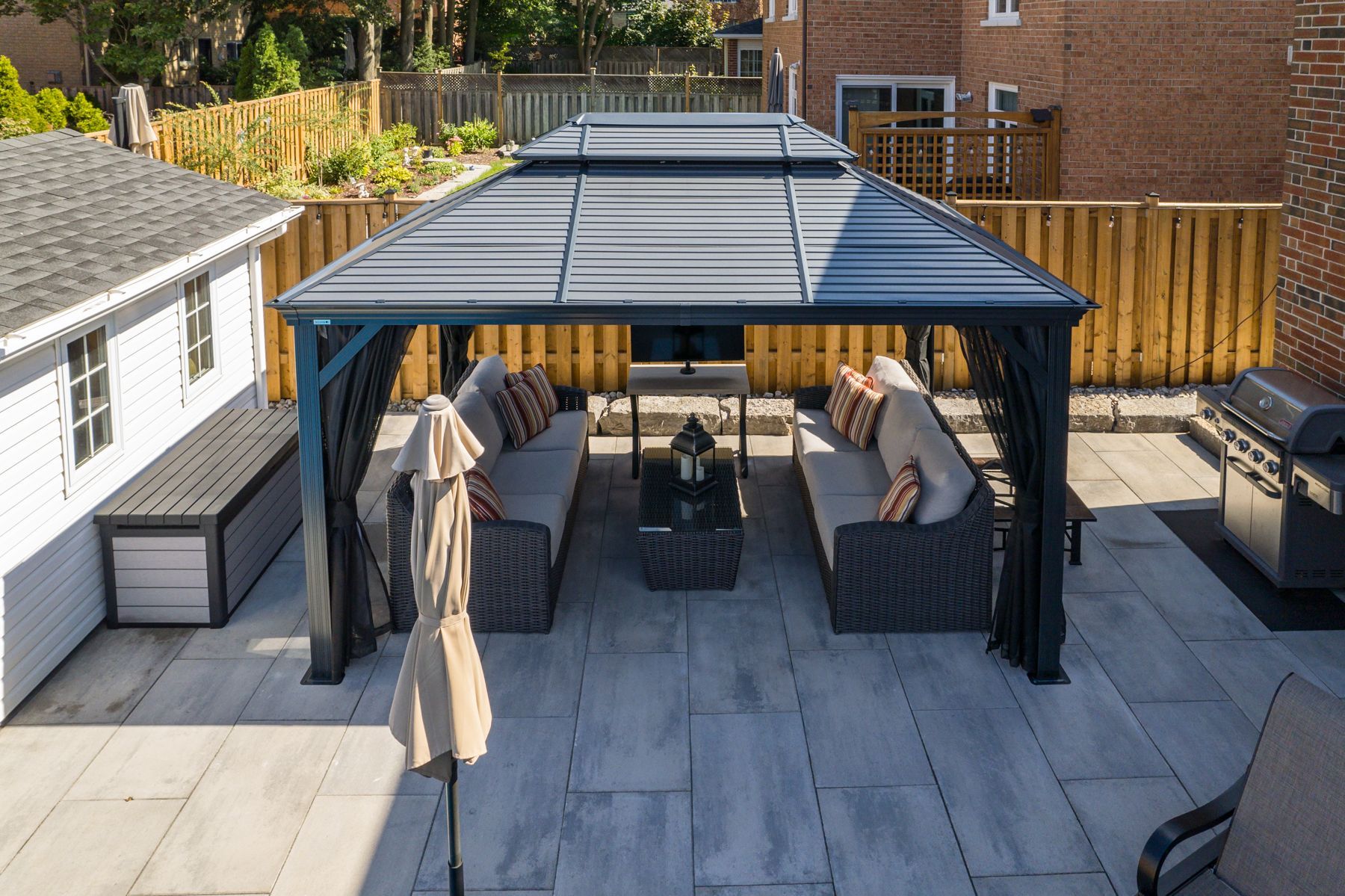 There is a gazebo with a couch and umbrella in the backyard.