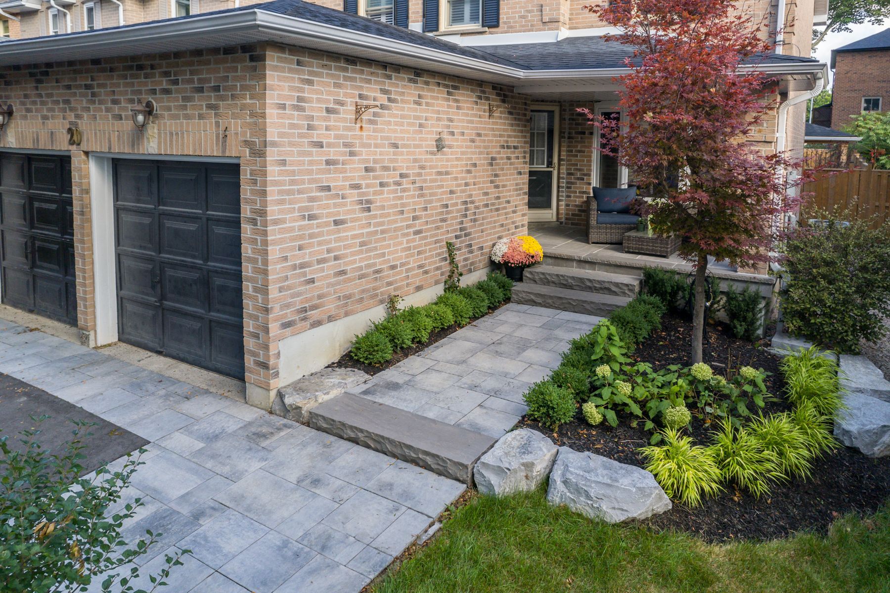 A brick house with a black garage door and a stone walkway leading to the front door.