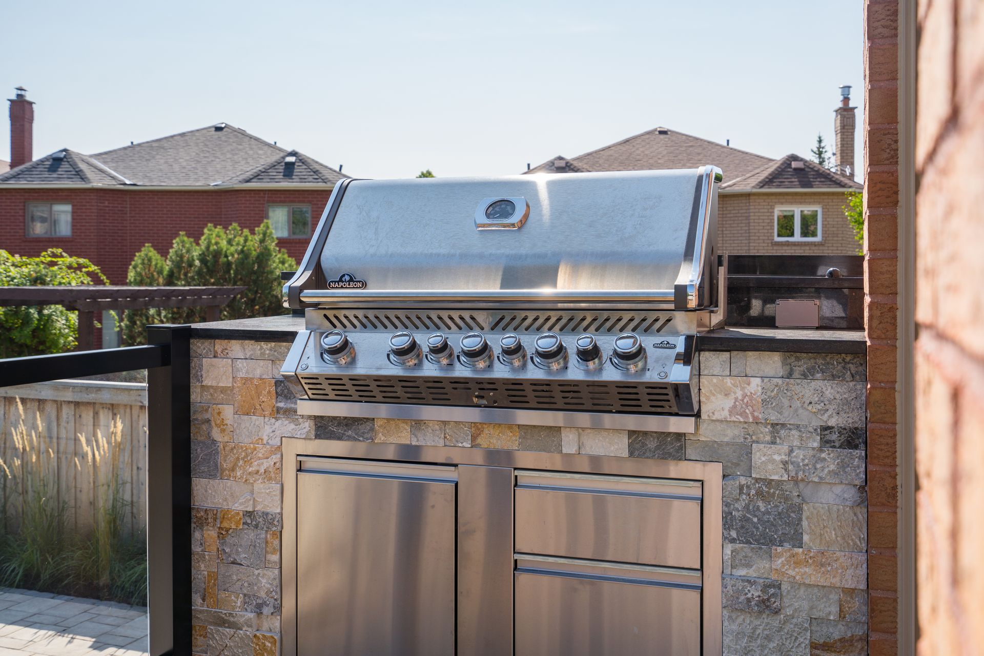 A stainless steel grill is sitting on top of a stone wall.