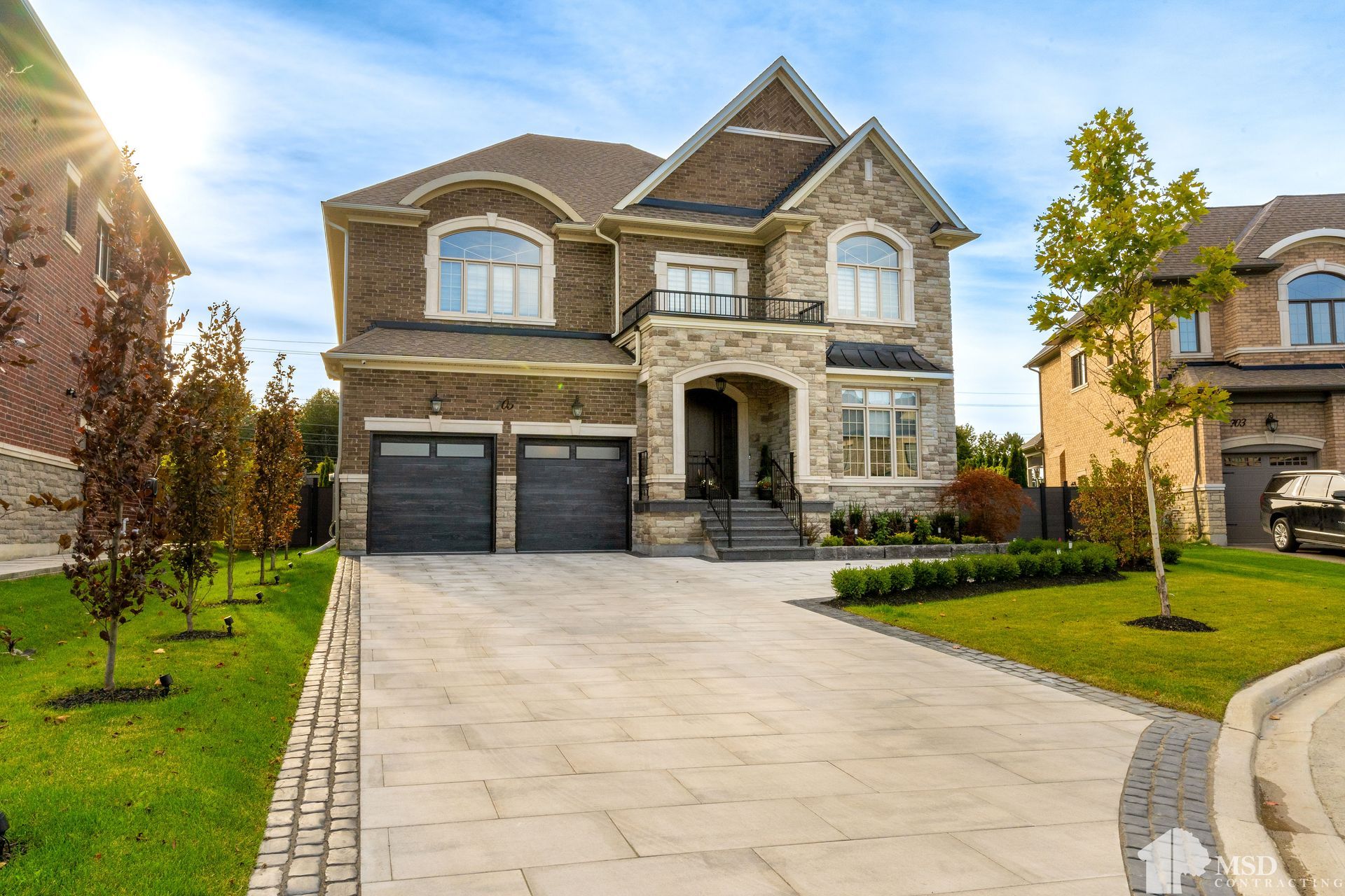 A large brick house with a large driveway and a car parked in front of it.