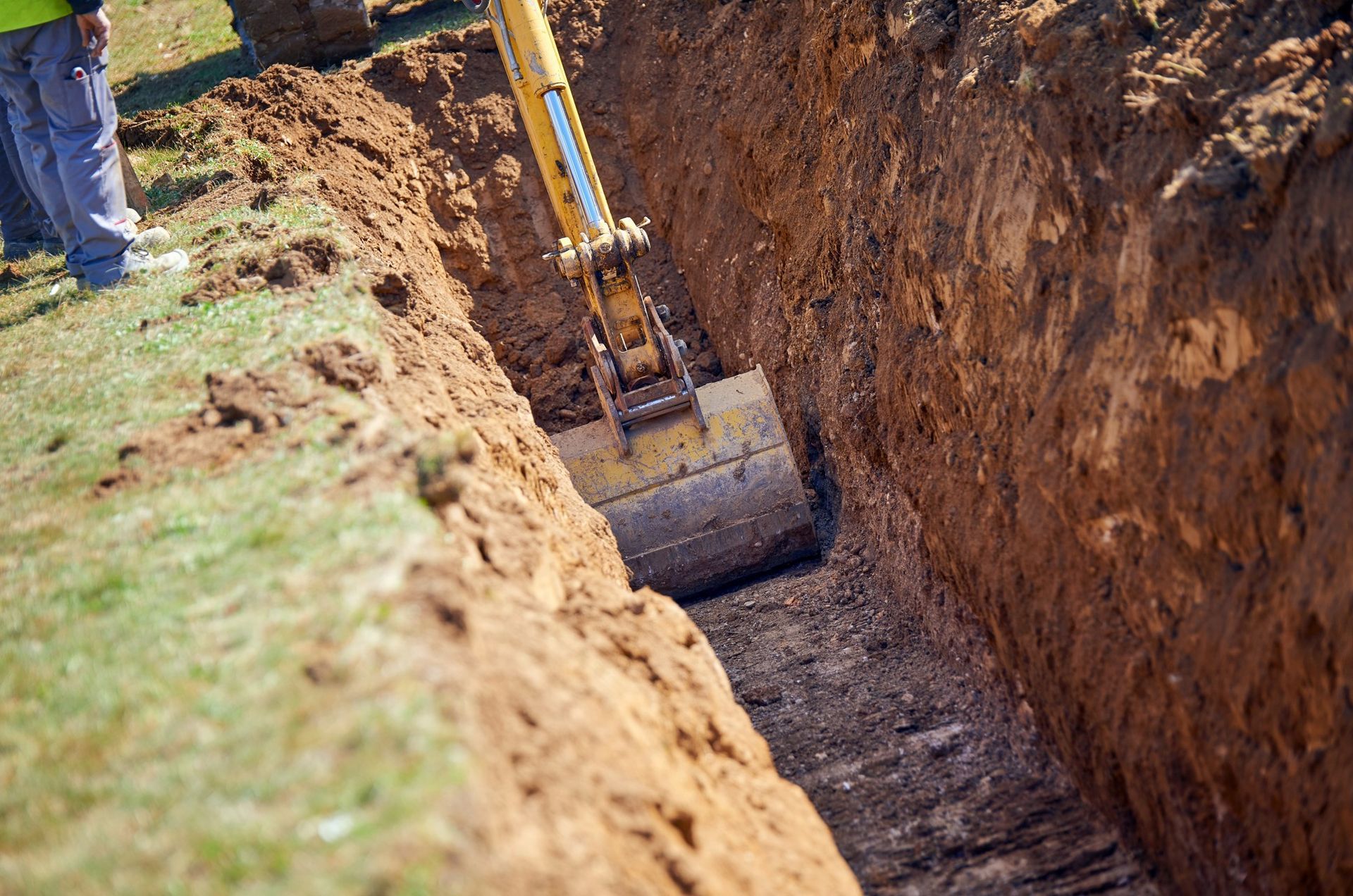 A yellow excavator is digging a hole in the ground.