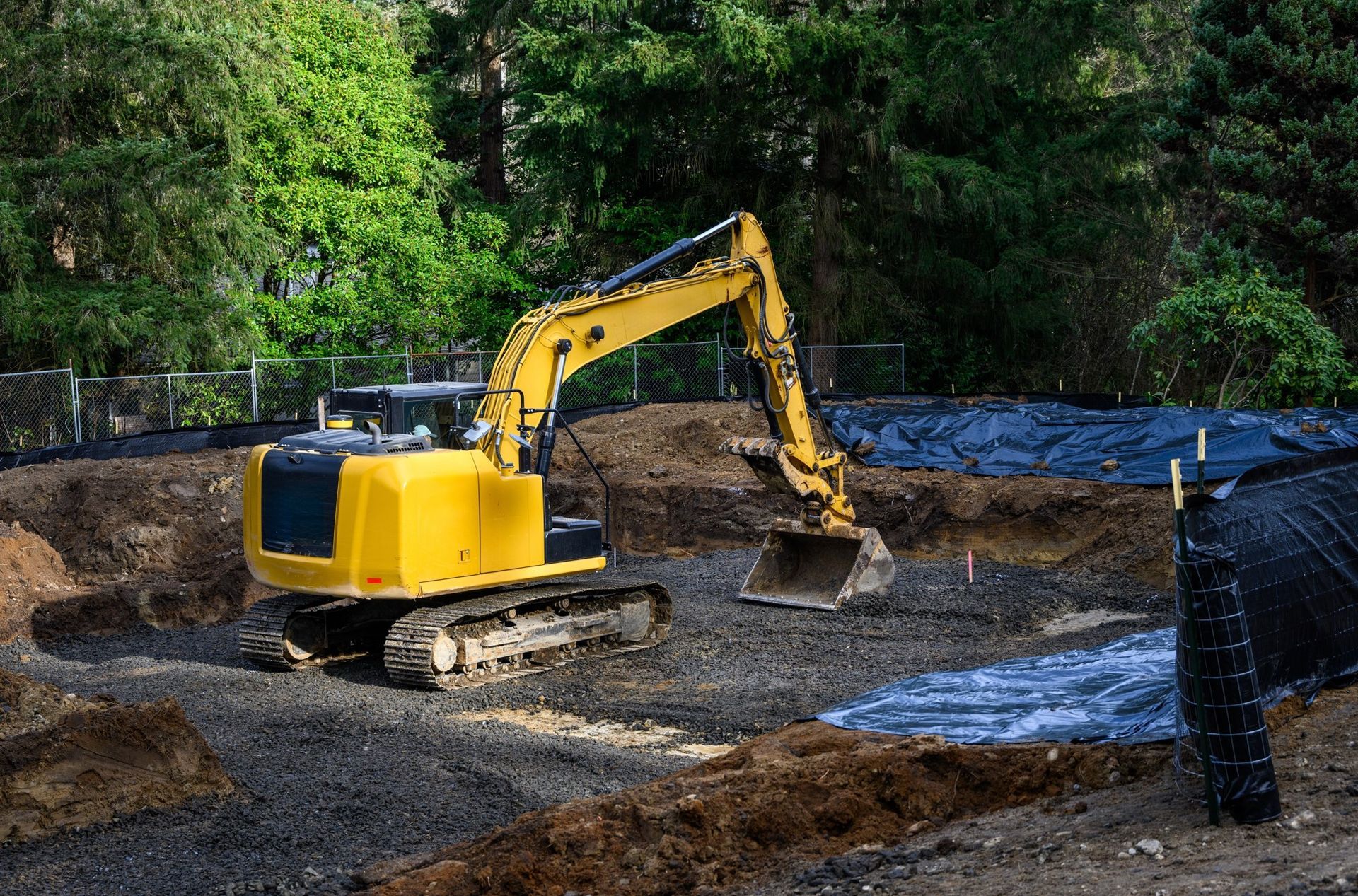 A yellow excavator is digging a hole in the dirt at a construction site.